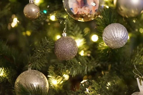 Sluitingen van kerstversieringen en lichtjes op een kerstboom met een wazige achtergrond — Stockfoto