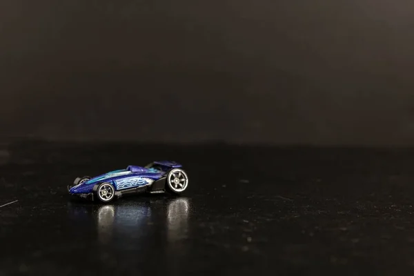 Photographie sélective d'une voiture sport jouet bleue sur une surface noire — Photo