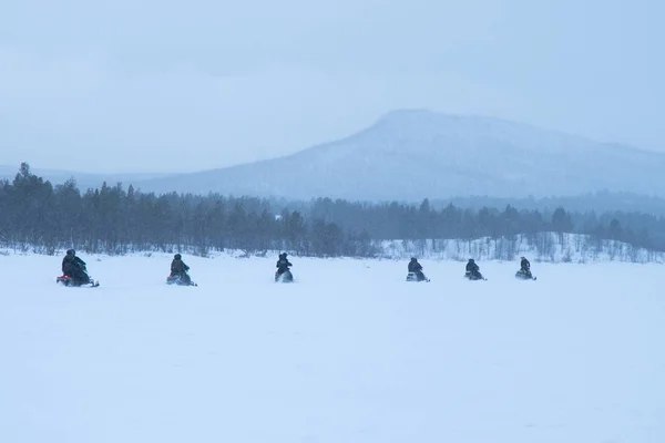 Snowy dag met mensen rijden op sneeuwscooters in het noorden van Zweden — Stockfoto