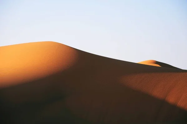 Prachtig uitzicht op een woestijn bij zonsondergang onder een lichtblauwe hemel — Stockfoto