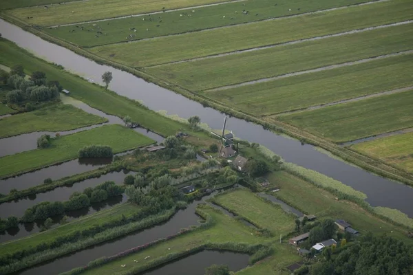 Hoge hoek opname van een waterstroom in het midden van grazige velden bij de Nederlandse polder — Stockfoto