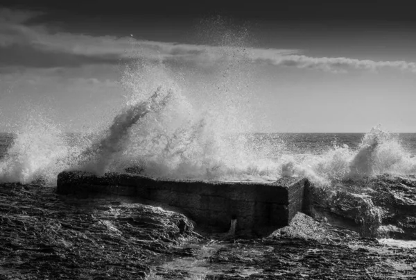 Šedá šupina mořských vln se zdmi kolem nich pod slunečním světlem a zamračenou oblohou — Stock fotografie