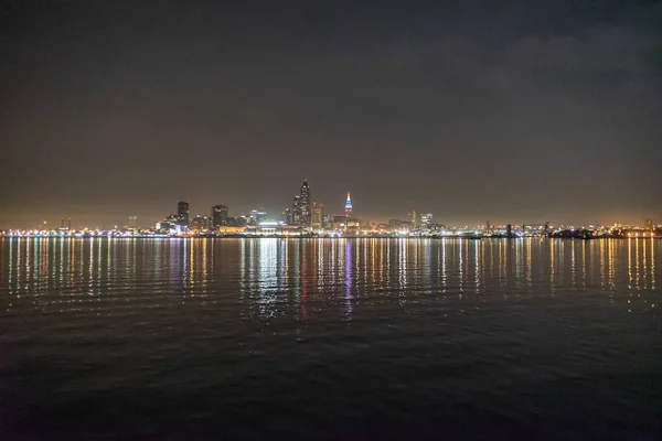 Luces de los edificios iluminados reflejadas en el agua oscura por la noche —  Fotos de Stock