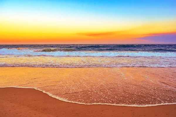 Пейзаж пляжа в окружении морских волн во время оранжевого заката вечером — стоковое фото