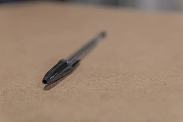 Selektiv fokusbild av en svart penna på en brun yta — Stockfoto
