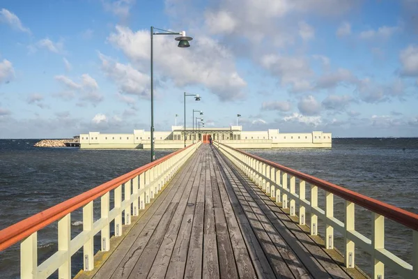 Seebrücke umgeben vom Meer und Gebäuden unter wolkenverhangenem Himmel und Sonnenlicht — Stockfoto