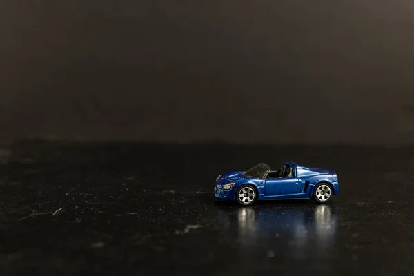 Photographie sélective d'une voiture sport jouet bleue sur une surface noire — Photo