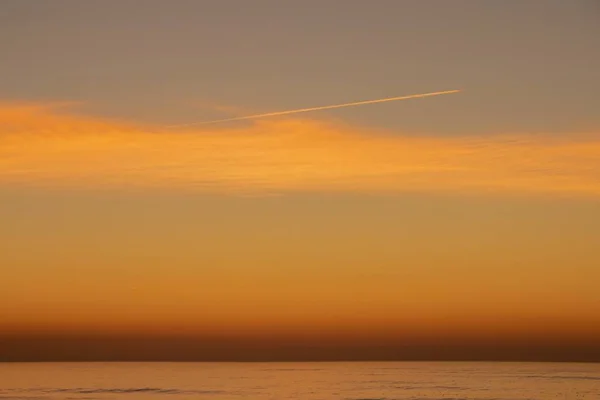 Belo pôr-do-sol laranja com uma pista de avião no céu acima do mar em Maceda, em Portugal — Fotografia de Stock