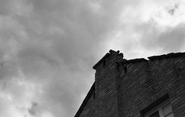 Niski kąt szary strzał ceglanego budynku pod pięknym chmurnym niebem — Zdjęcie stockowe