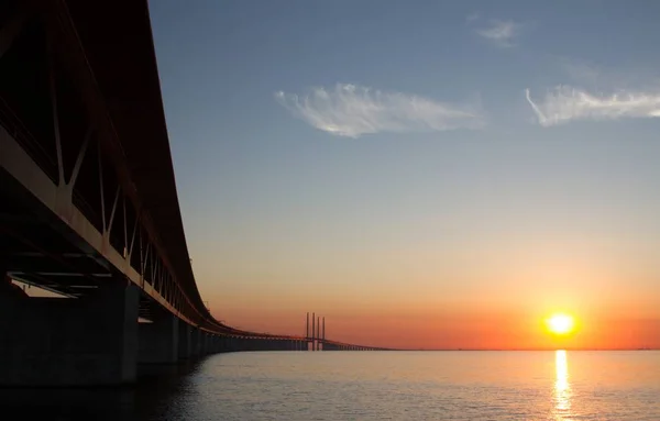Hermoso tiro de un puente sobre el mar con el sol brillando en la distancia. —  Fotos de Stock