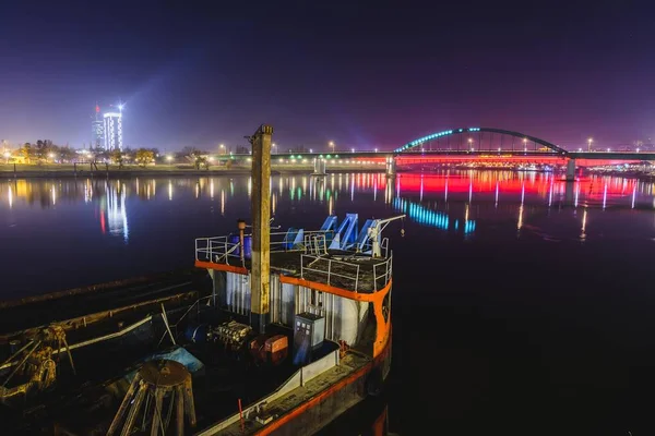 Vue de la partie d'un vieux navire, vieux pont ferroviaire et lumières lointaines de la ville la nuit, Belgrade, Serbe — Photo