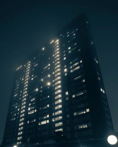 Baixo ângulo tiro de um apartamento da cidade no nevoeiro à noite — Fotografia de Stock