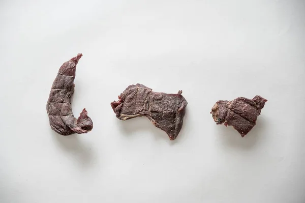 Colpo ad angolo alto di pezzi di carne secca su una superficie bianca — Foto Stock