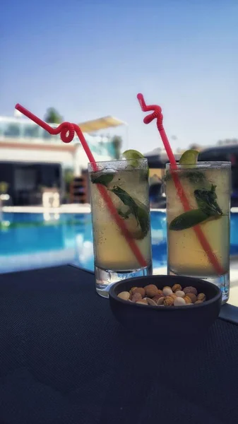 Vertical shot of cold refreshing drinks with a bowl of nuts at the pool — ストック写真