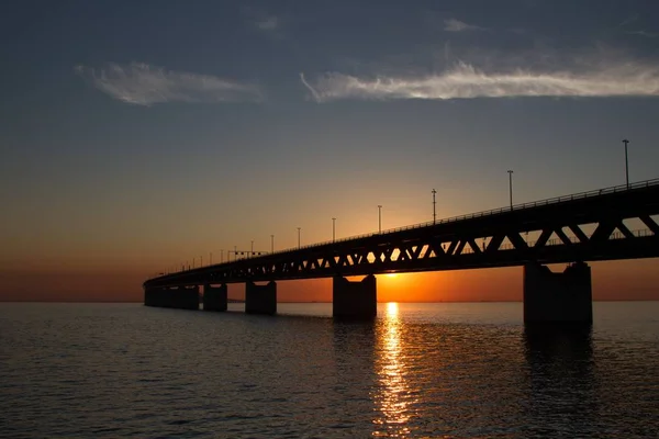 Silhouette del puente Oresundsbron sobre el agua con el sol en el fondo. —  Fotos de Stock