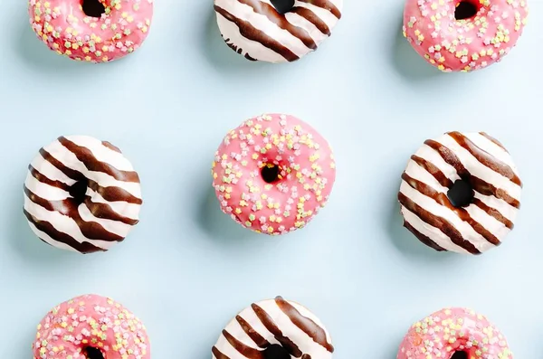 Tiro de close-up de alto ângulo de deliciosos donuts em uma superfície azul clara - perfeito para um papel de parede legal — Fotografia de Stock