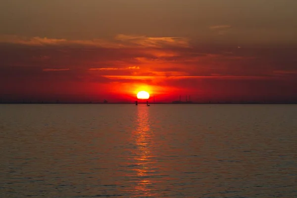 Hermosa toma del mar con un sol rojo en el cielo — Foto de Stock