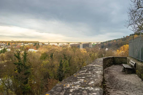 Collina immersa nel verde con un ponte e gli edifici sotto la luce del sole sullo sfondo — Foto Stock