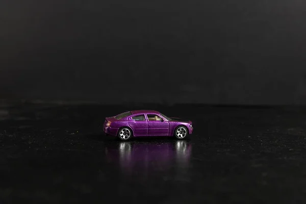 Filme de foco seletivo de um carro de brinquedo roxo em uma superfície preta — Fotografia de Stock