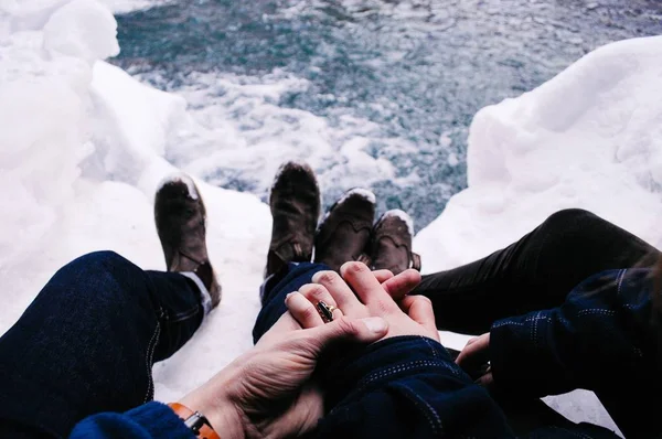 Στιγμιότυπο υψηλής γωνίας δύο αρσενικών που κρατούν το ένα χέρι του άλλου ενώ κάθονται στο χιονισμένο έδαφος — Φωτογραφία Αρχείου