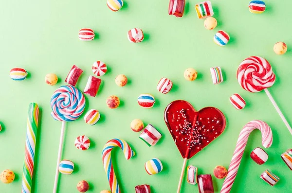 Closeup shot of candy canes and other candies on a green background - perfcet for a cool wallpaper
