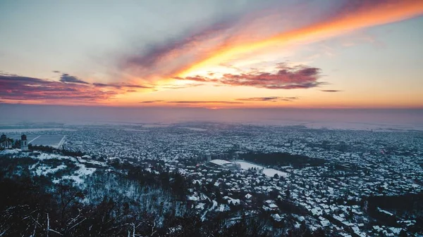 Hög vinkel skott av en hisnande solnedgång landskap över staden täckt med snö på vintern — Stockfoto