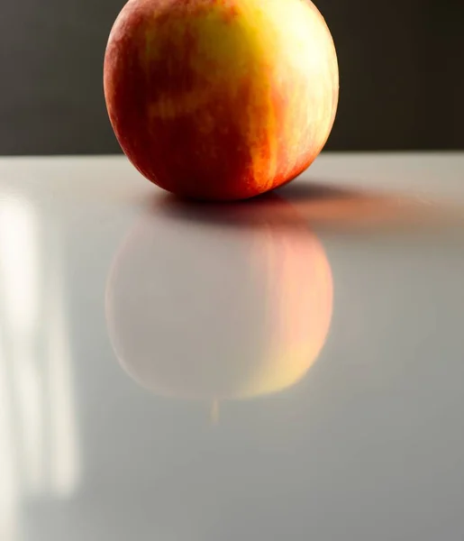 Fechar de uma maçã vermelha refletindo sobre a mesa sob as luzes com um fundo embaçado — Fotografia de Stock