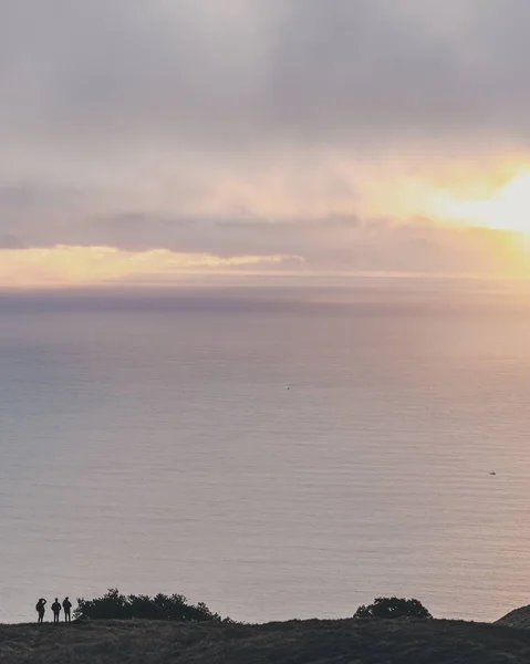 Függőleges felvétel három emberről, akik a távolban állnak, és a gyönyörű tengert nézik. — Stock Fotó