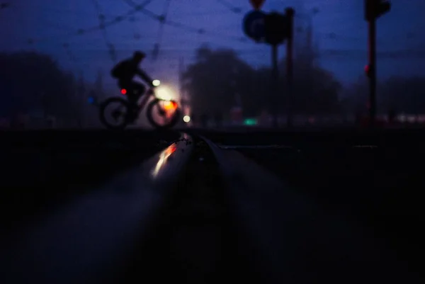 Pessoa montando uma bicicleta através da rua capturada à noite — Fotografia de Stock