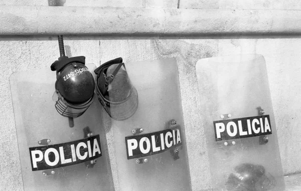 Šedá stupnice záběru policejních štítů a helmy na chodníku vedle budovy — Stock fotografie