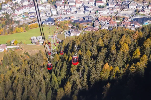 Belo tiro de teleféricos acima de uma montanha arborizada com edifícios à distância — Fotografia de Stock