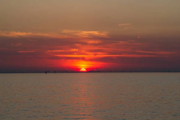 A beautiful shot of the sea with a red sun in the background