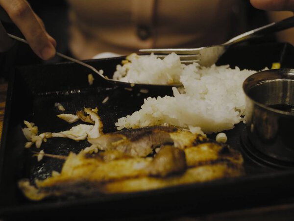 Closeup shot of a person eating rice and fish in a dark setting — Stock Photo, Image