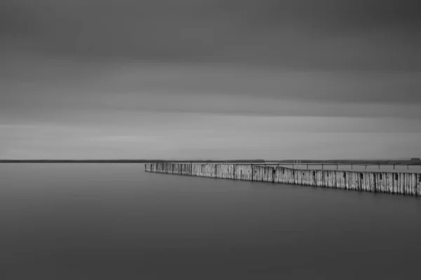 Šedivý Záběr Dlouhé Molo Moře Pod Bouřkovými Mraky — Stock fotografie