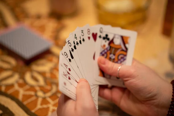 Foco seletivo de uma mão de cartas de jogo realizada por uma pessoa com um fundo embaçado — Fotografia de Stock