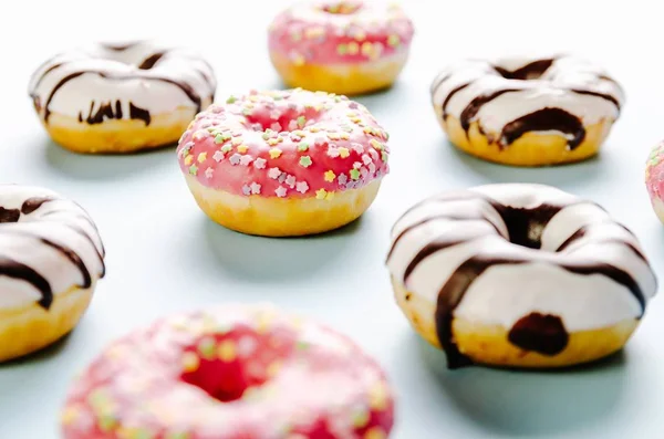 Nahaufnahme köstlicher Donuts auf hellblauer Oberfläche - perfekt für eine coole Tapete — Stockfoto