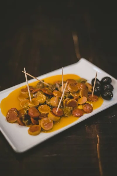 Вертикальный снимок тарелки с нарезанной колбасой и черными оливками на белой тарелке — стоковое фото