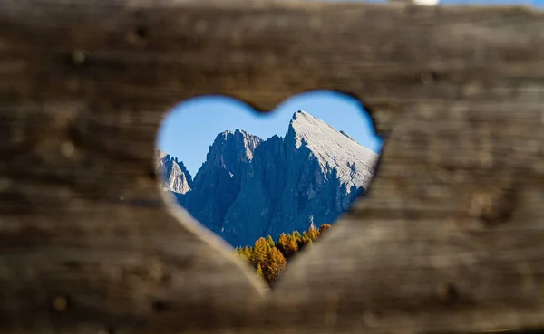 Selective focus shot from a heart-shaped hole of mountains in the distance in dolomite Italy — 스톡 사진