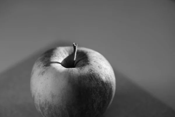Échelle de gris d'une pomme réfléchissant sur la table avec un fond flou — Photo
