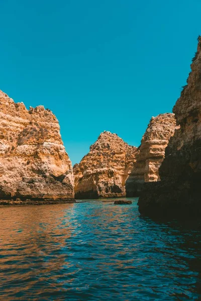 晴れた日に海に反射する岩の崖の垂直ショット — ストック写真