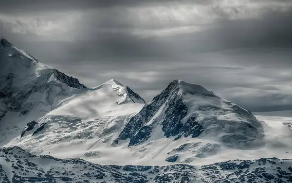 Krásná scenérie pohoří pokrytého sněhem pod zamračenou oblohou — Stock fotografie