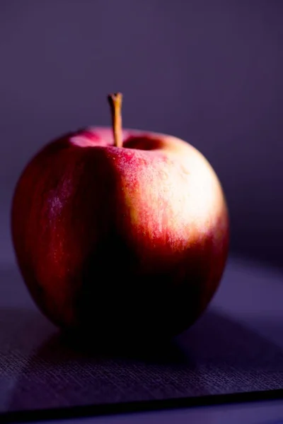 Gros plan d'une pomme rouge réfléchissant sur la table sous les lumières avec un fond flou — Photo