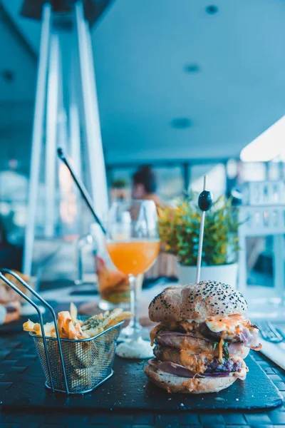 Вертикальный Снимок Гамбургера Картошкой Фри Апельсиновым Соком Размытом Фоне — стоковое фото