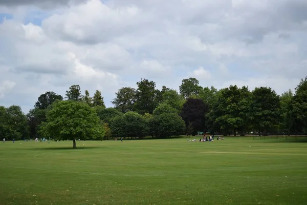 Persone che si rilassano sul terreno erboso di Oxford, l'Uk sotto il cielo nuvoloso — Foto Stock