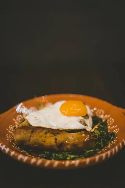 Colpo verticale di un piatto con uova, salsiccia e foglie vegetali — Foto Stock