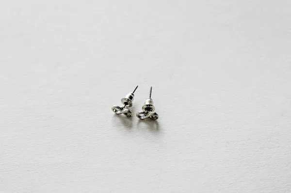 Eine Hochwinkelaufnahme Von Zwei Kleinen Silbernen Ohrringen Auf Einer Weißen — Stockfoto