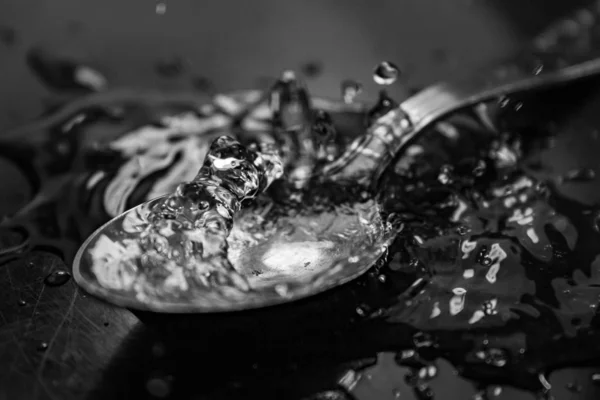 Graustufige Nahaufnahme Von Wassertropfen Auf Einem Löffel Auf Einem Tisch — Stockfoto