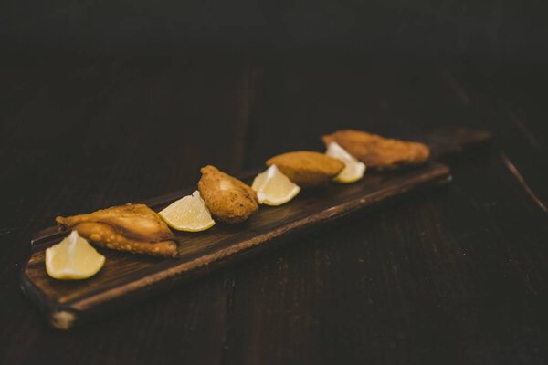 High angle shot of fried food near lemon sliced on a wooden surface — Stock Photo, Image