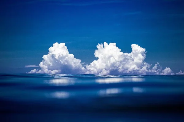 A closeup of a sea under a blue sky with the clouds on the background