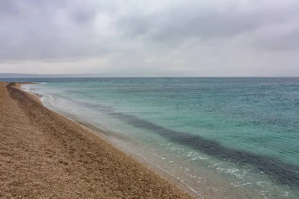Paisaje de una playa rodeada por el mar bajo un cielo nublado — Foto de Stock